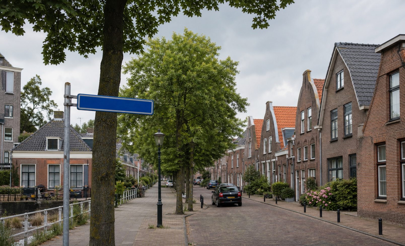Straatnaambord aan een groene Nederlandse woonstraat met oude huizen